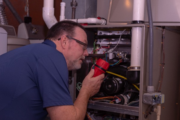 Man In Blue Shirt Repairing Furnace In House